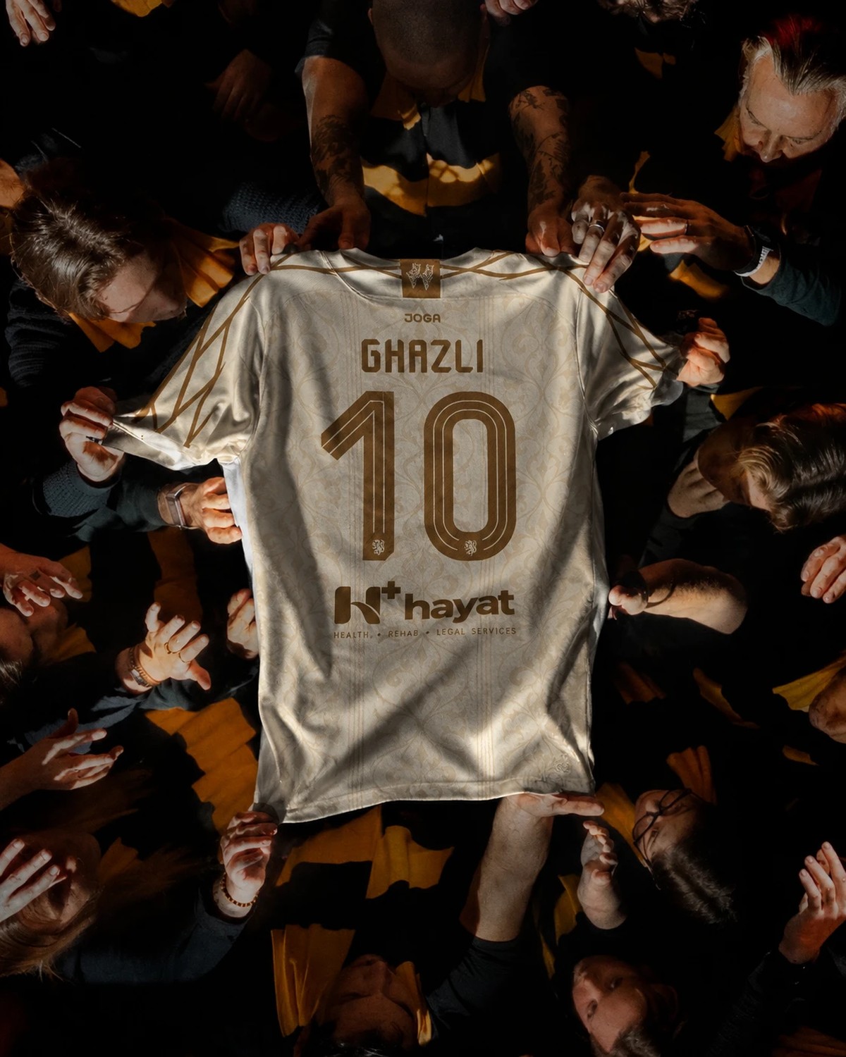 The white kit held up by the squad, Ghazli and the number 10 on the back